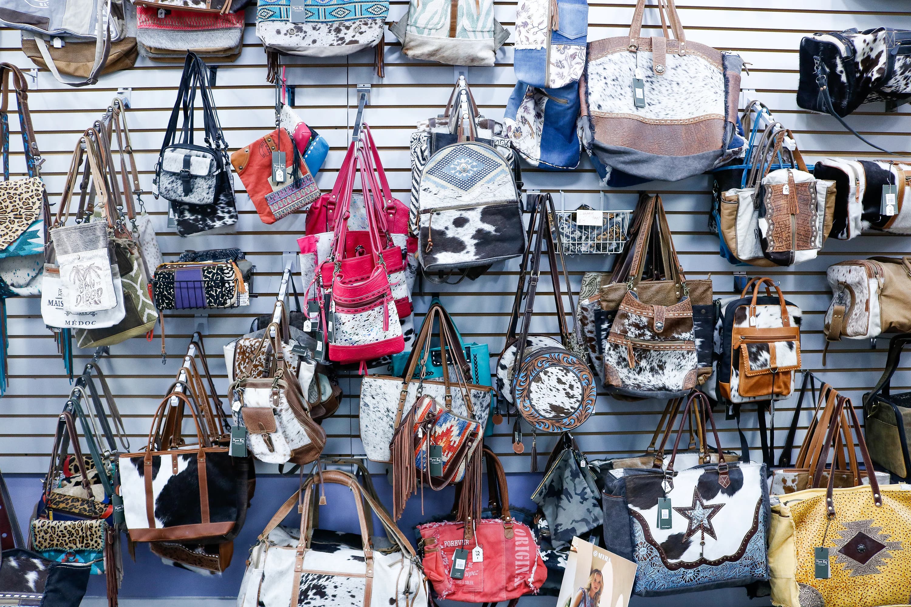 Wall of handmade cowhide handbags and leather totes