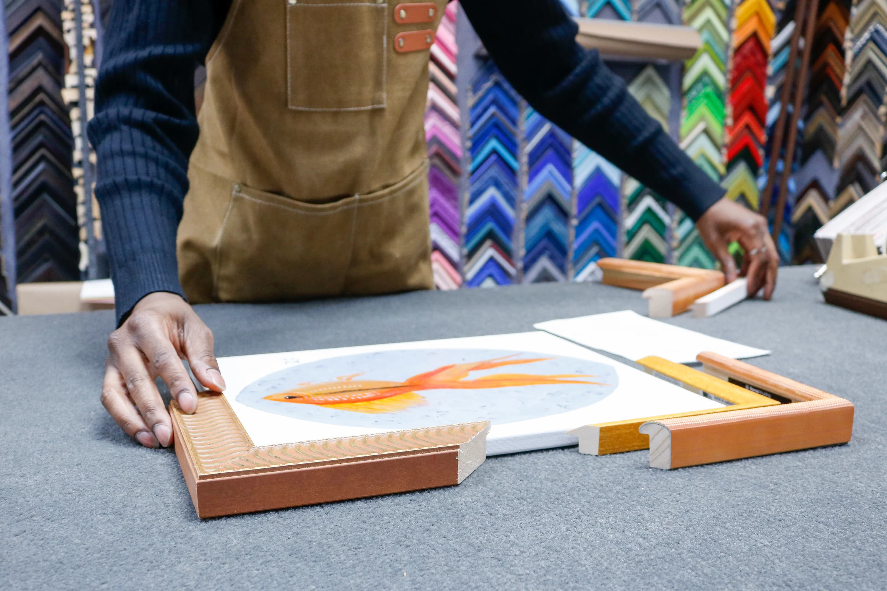 Hands carefully assembling a frame around a goldfish print